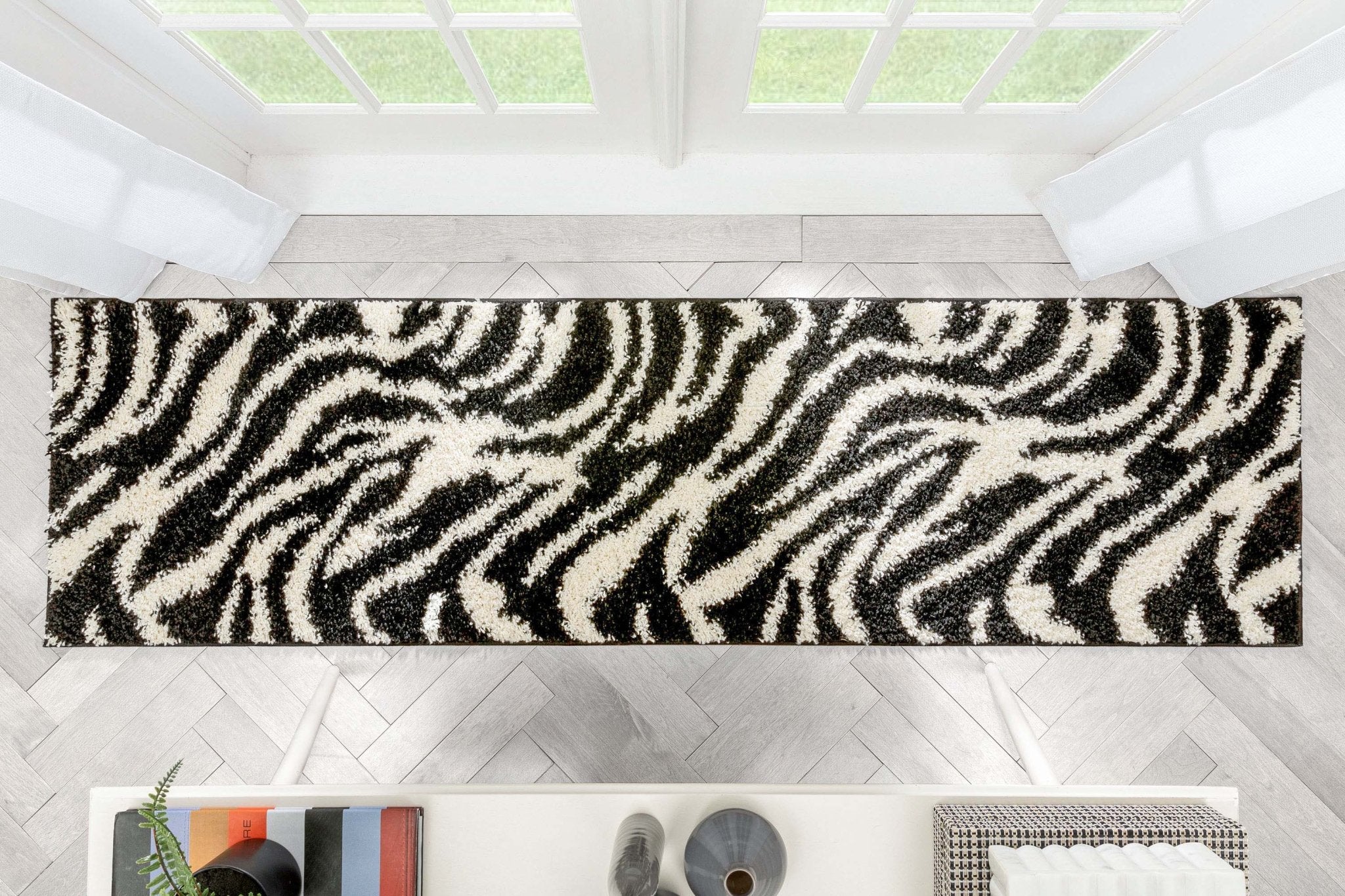 Safari Zebra Black Contemporary Shag Rug - Well Woven - Top-down view of the rug stretching across a hallway or entryway, showing the full graphic pattern.