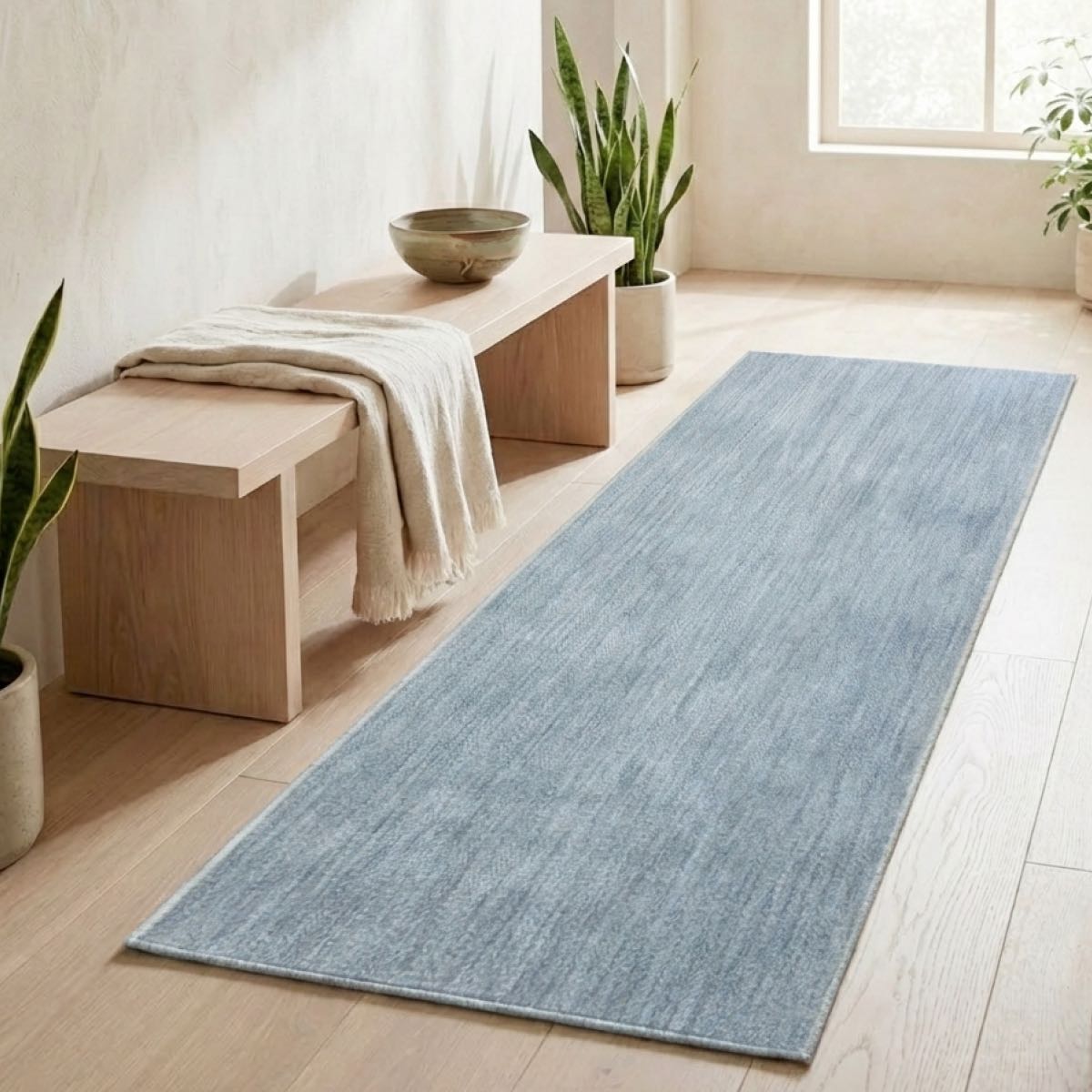 COD-17 - Long light blue and beige runner rug on a wooden floor with a bench and plants in a bright room.