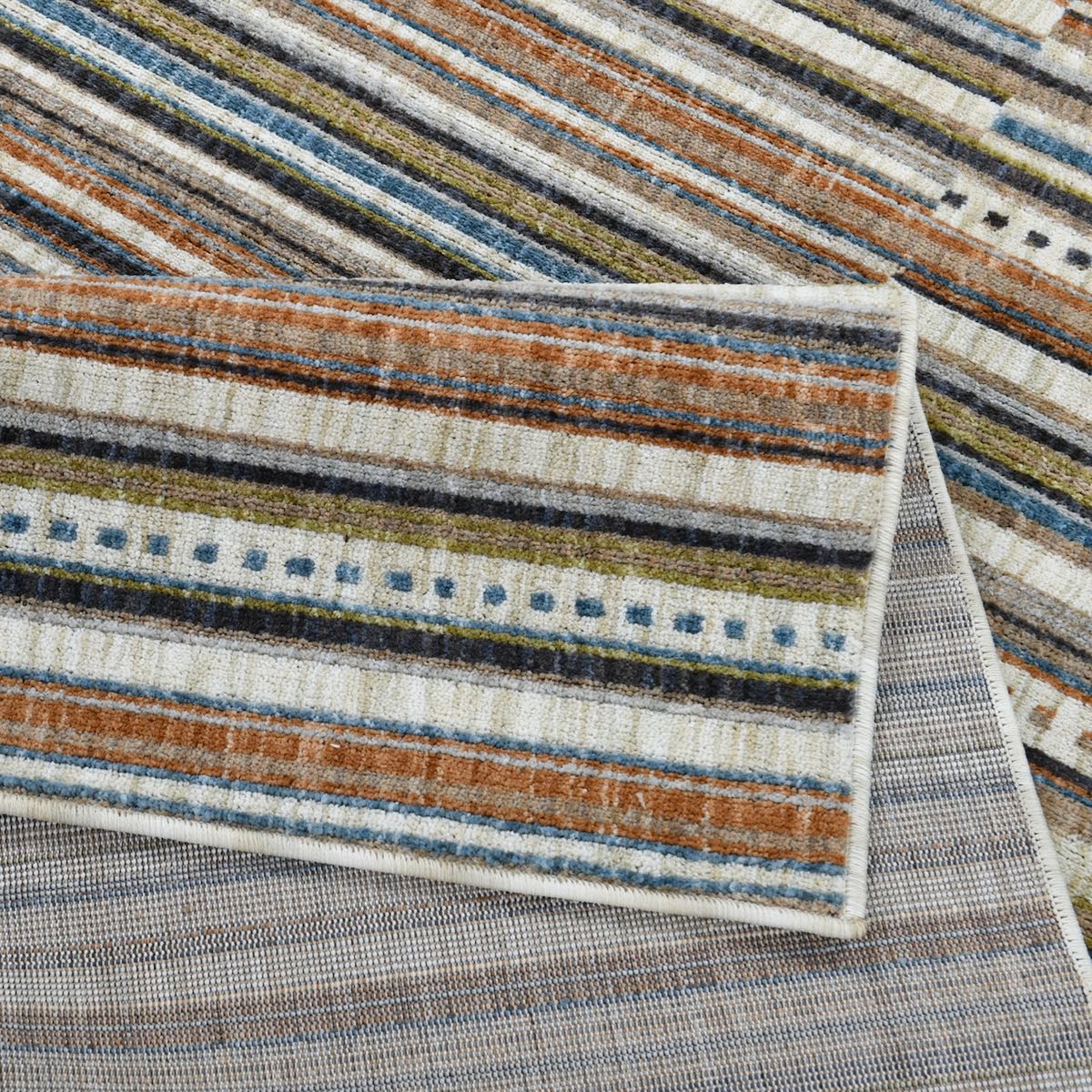 COD-41 Well Woven Thane Washable Rug: Close-up of a striped rug folded over itself to highlight its with brown, blue, and beige colors.