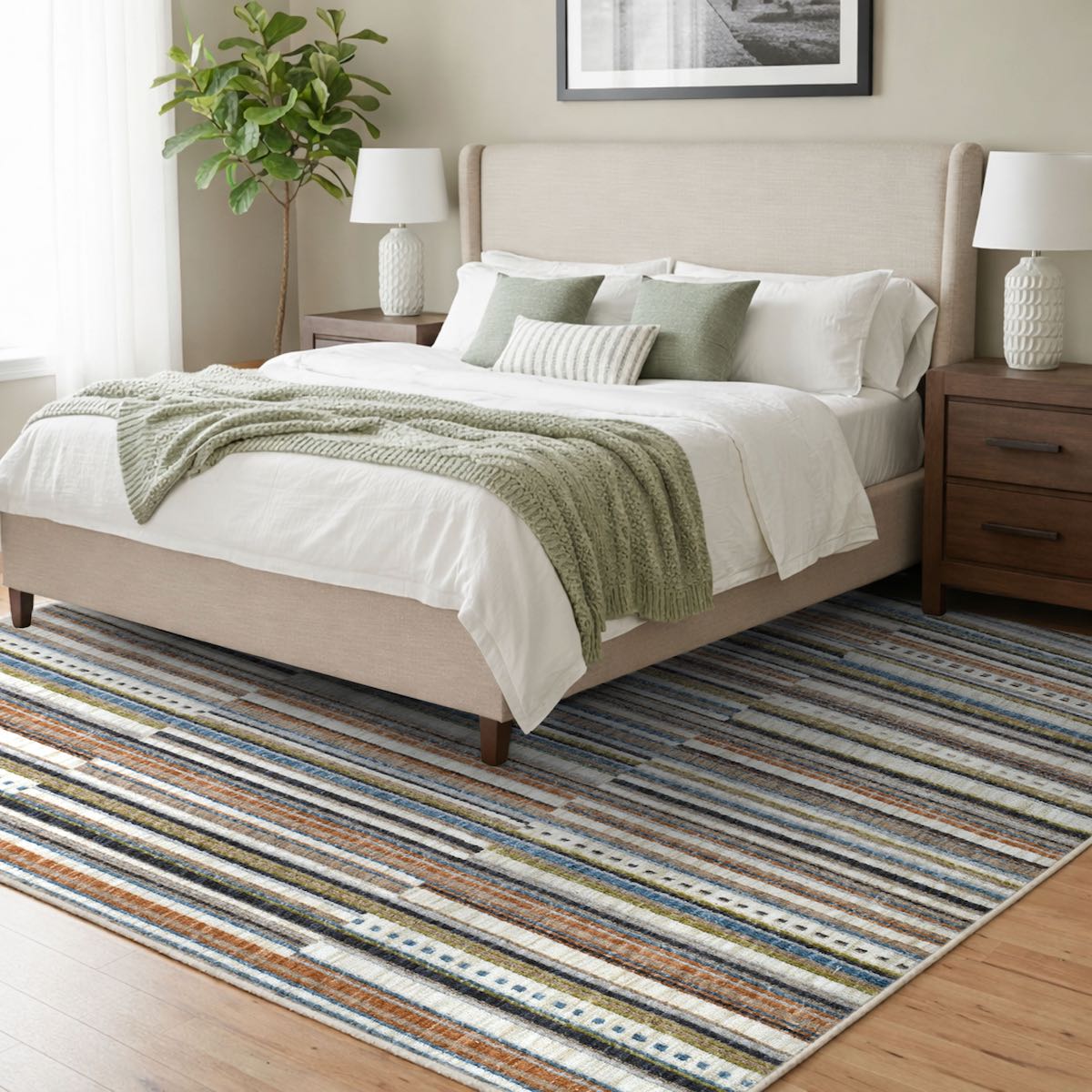 COD-41 Well Woven Thane Washable Rug - Neatly made bed with white sheets and a green blanket on a striped washable area rug of various colors (cream, blue, grey, rust) in a bedroom setting.