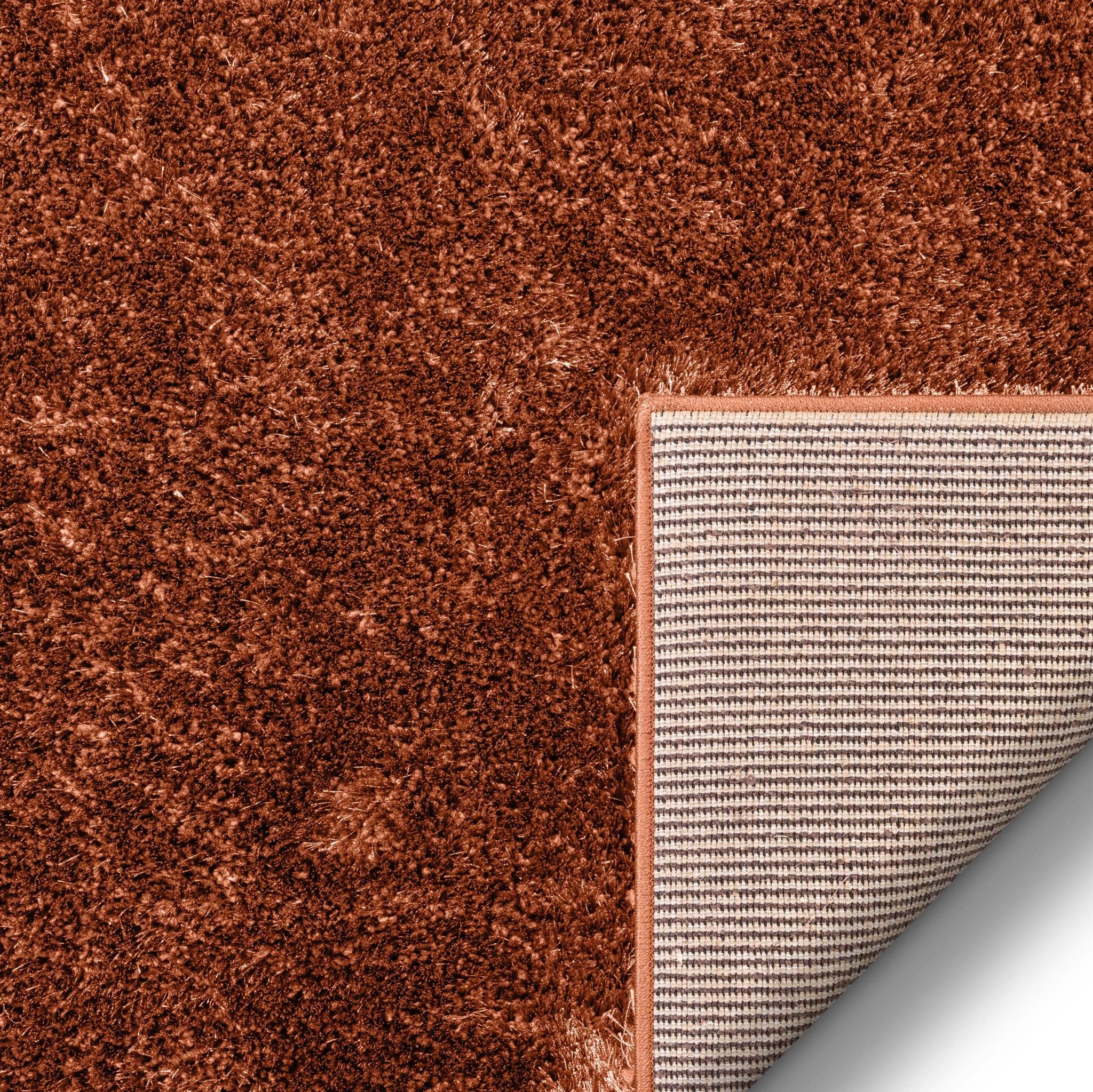 A detail showing the Feather Collection Liza Terracotta Shag Rug's jute backing