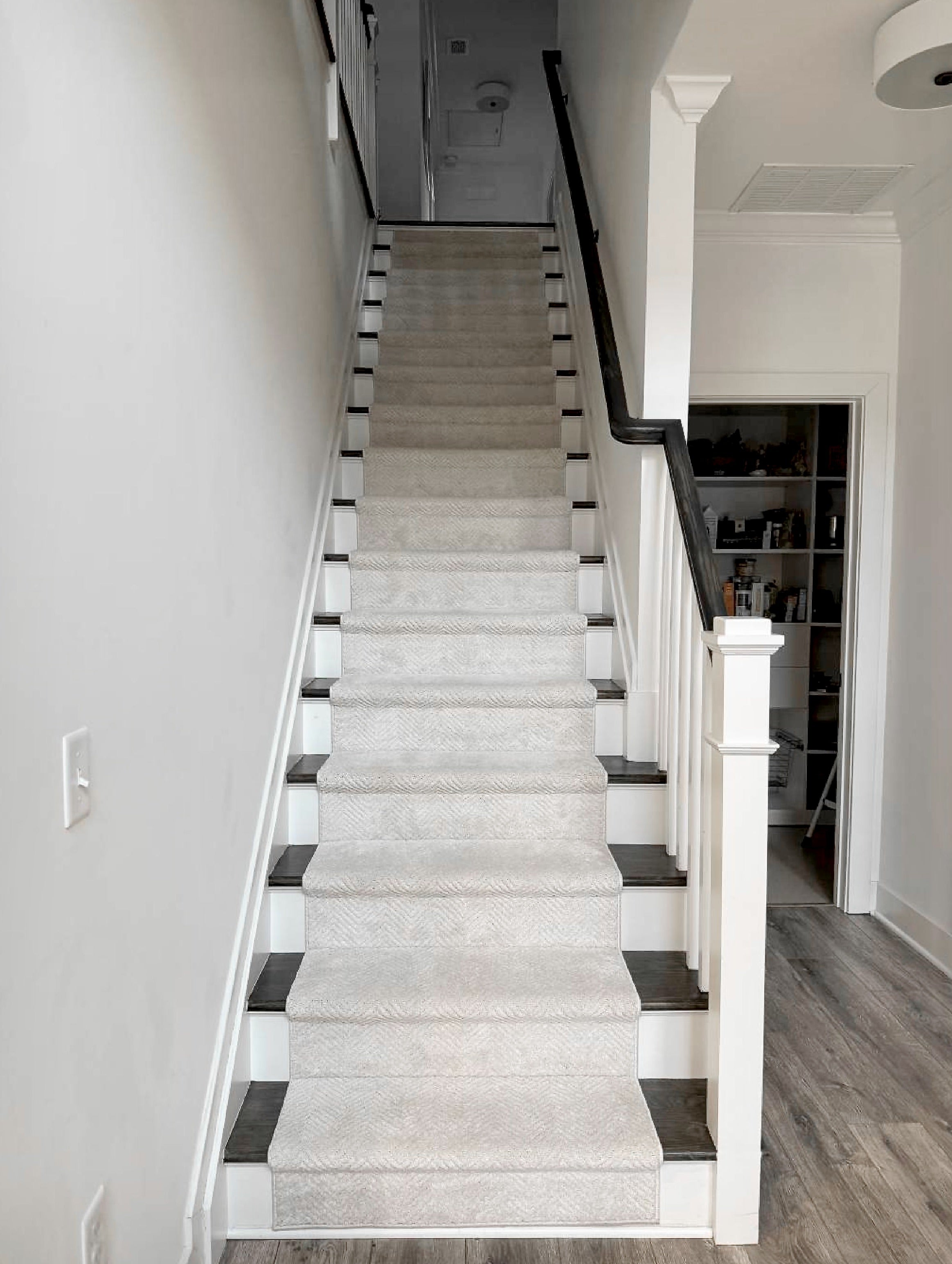Staircase with ivory carpet and wood stair treads in a home interior.