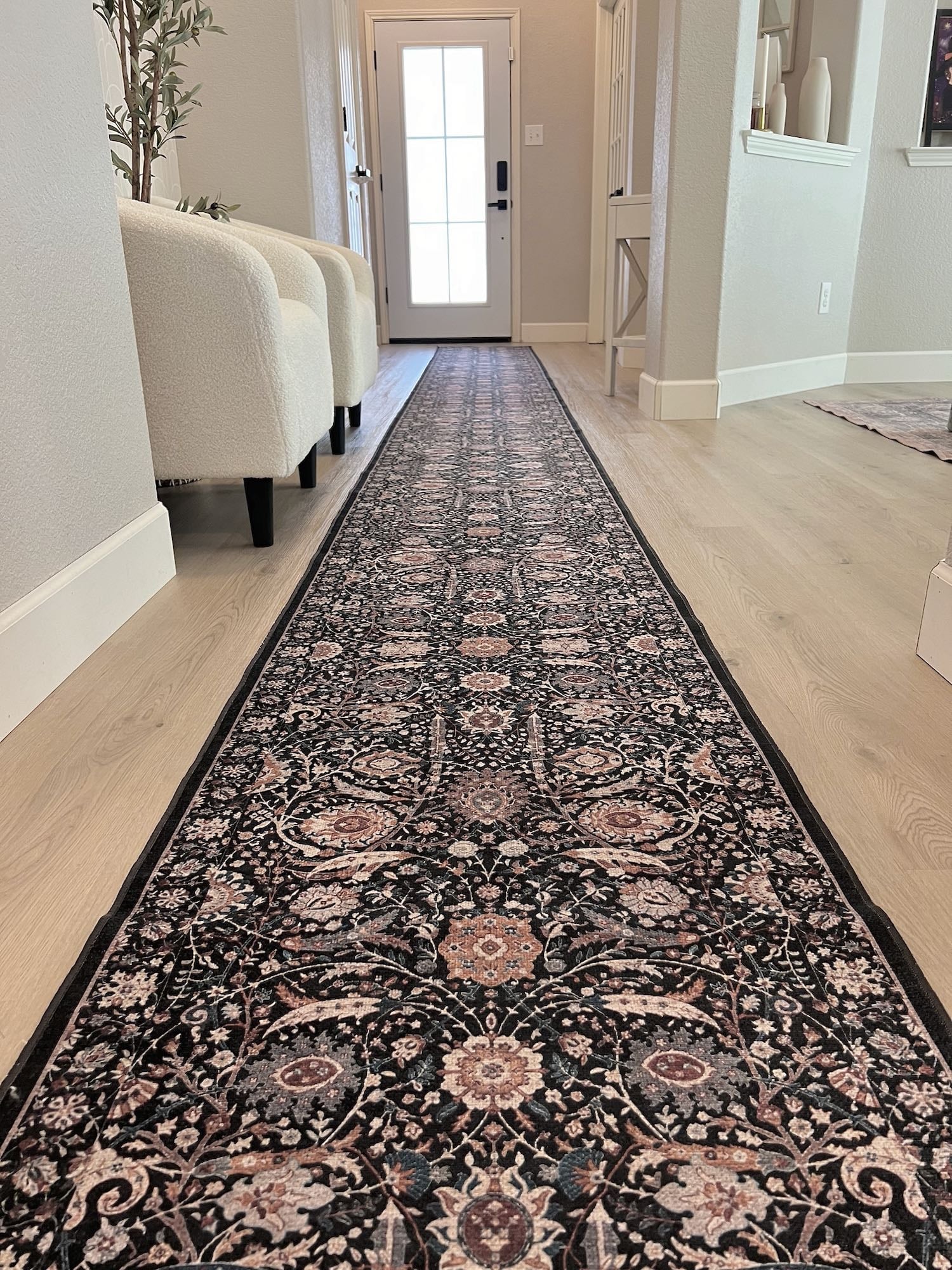Long, patterned floral runner rug on a light wood floor in a hallway.