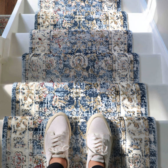 IND-106 Patterned blue and beige staircase runner rug with a person wearing white sneakers standing on it.