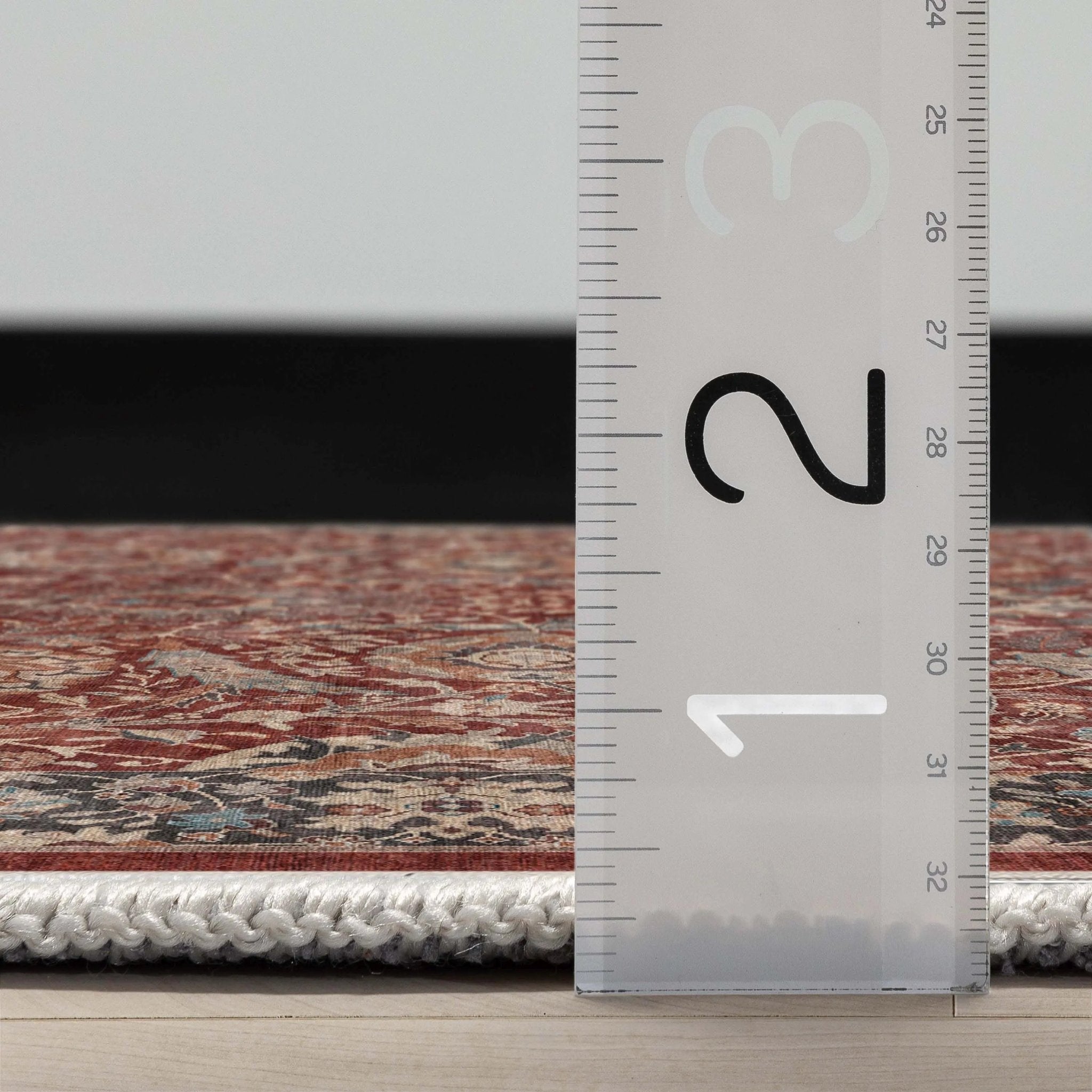 Close up profile of the Asha Liana Red Flatwoven Runner Rug with a ruler showing measurements on a wooden floor.
