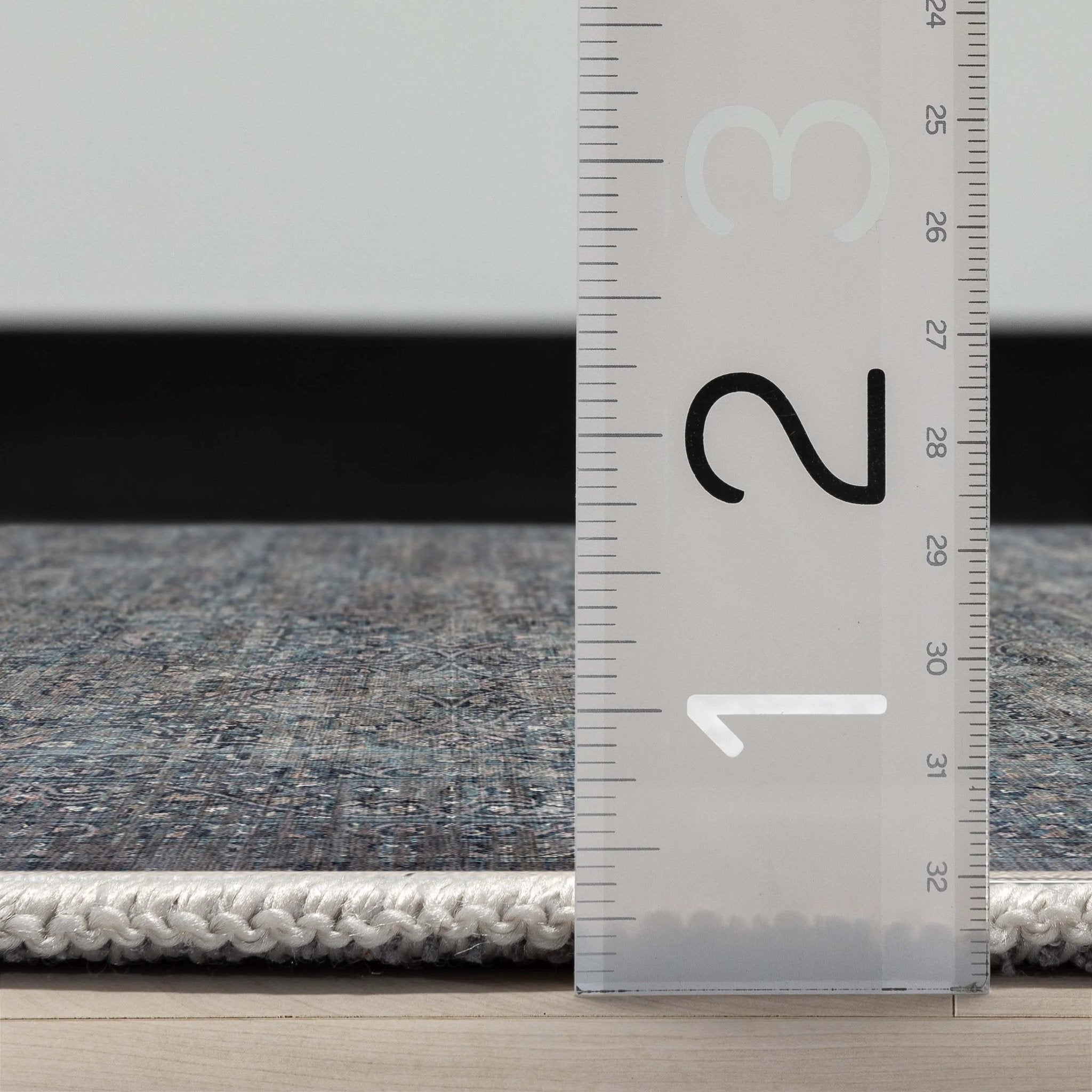 Close up profile of the Juliette Flatwoven Runner Rug with a ruler showing measurements on a wooden floor.