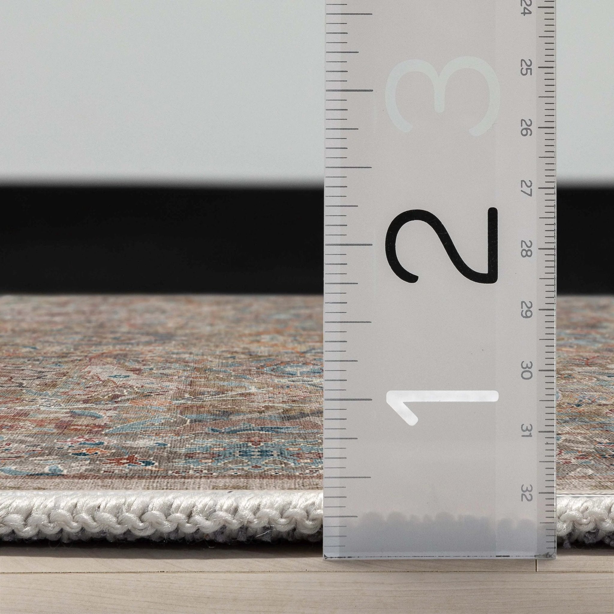 Close up profile of the Asha Emilia Flatwoven Runner Rug with a ruler showing measurements on a wooden floor.