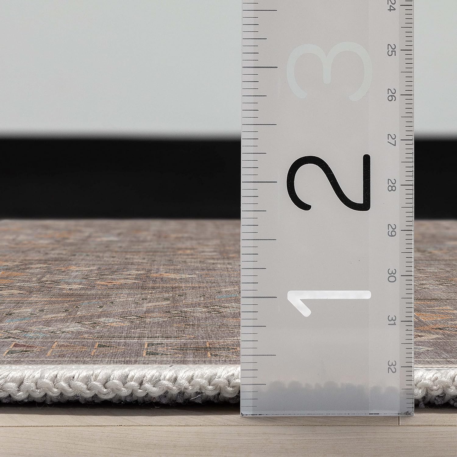 A side profile of the Asha Anya Flatwoven Custom Runner Rug with a ruler showing measurements on a wooden floor