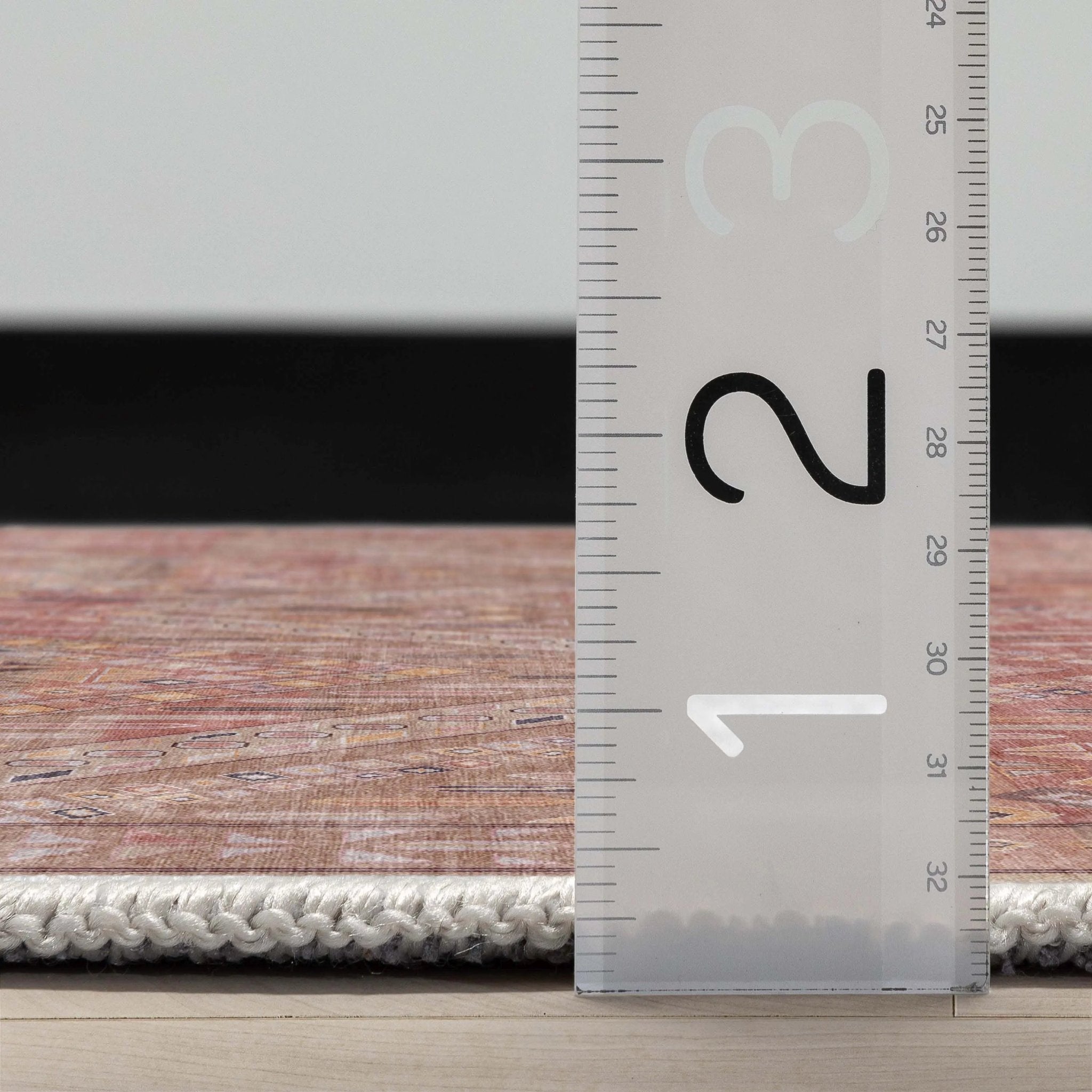A side profile of the Asha Anya Flatwoven Custom Runner Rug with a ruler showing measurements on a wooden floor