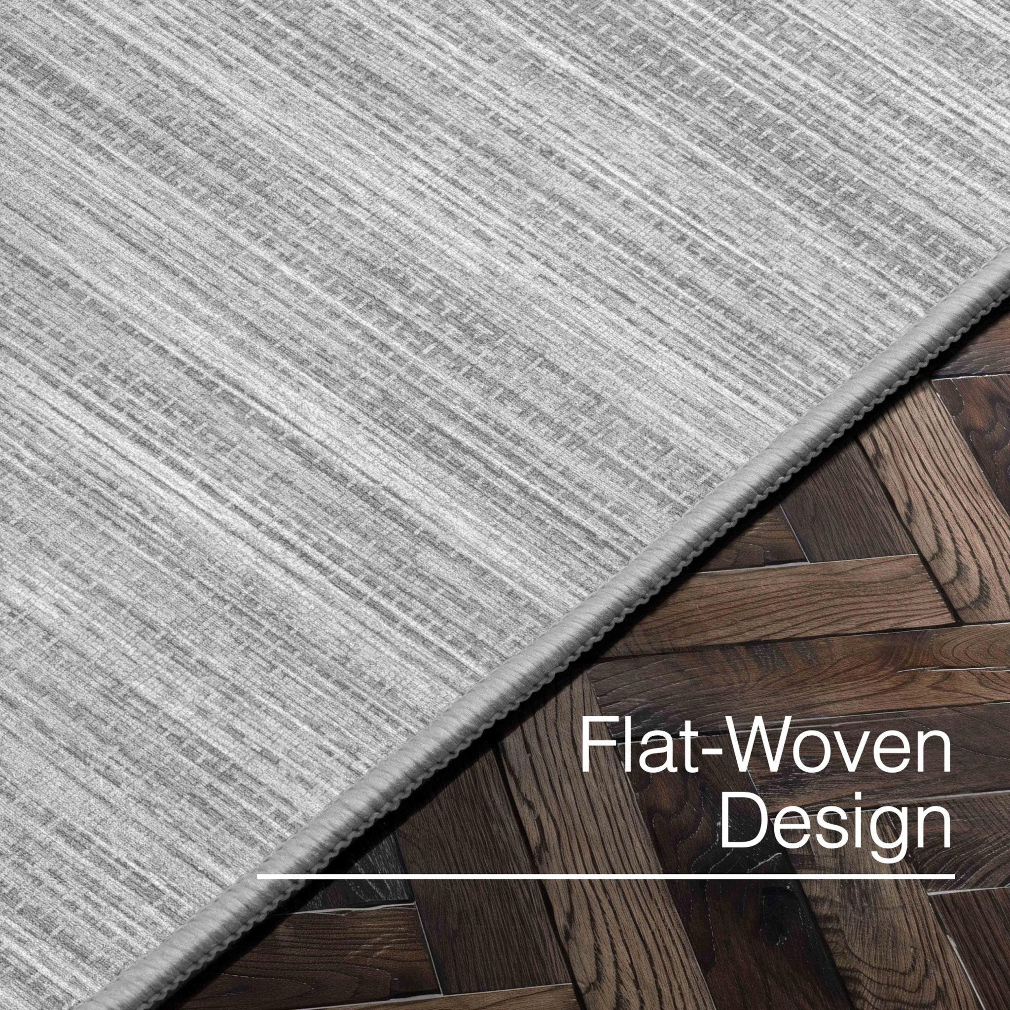 Edwin Custom Rug - Monochrome Striation , Flat Pile, Easy  Clean, Customizable for Your Space - Well Woven - Angled close-up of the light grey rug with text: “Flat-Woven Design.”