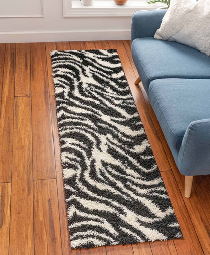 Safari Zebra Black Contemporary Shag Rug - Well Woven - Zebra-print runner rug placed in front of a blue sofa on wood flooring, adding a bold accent to the space.