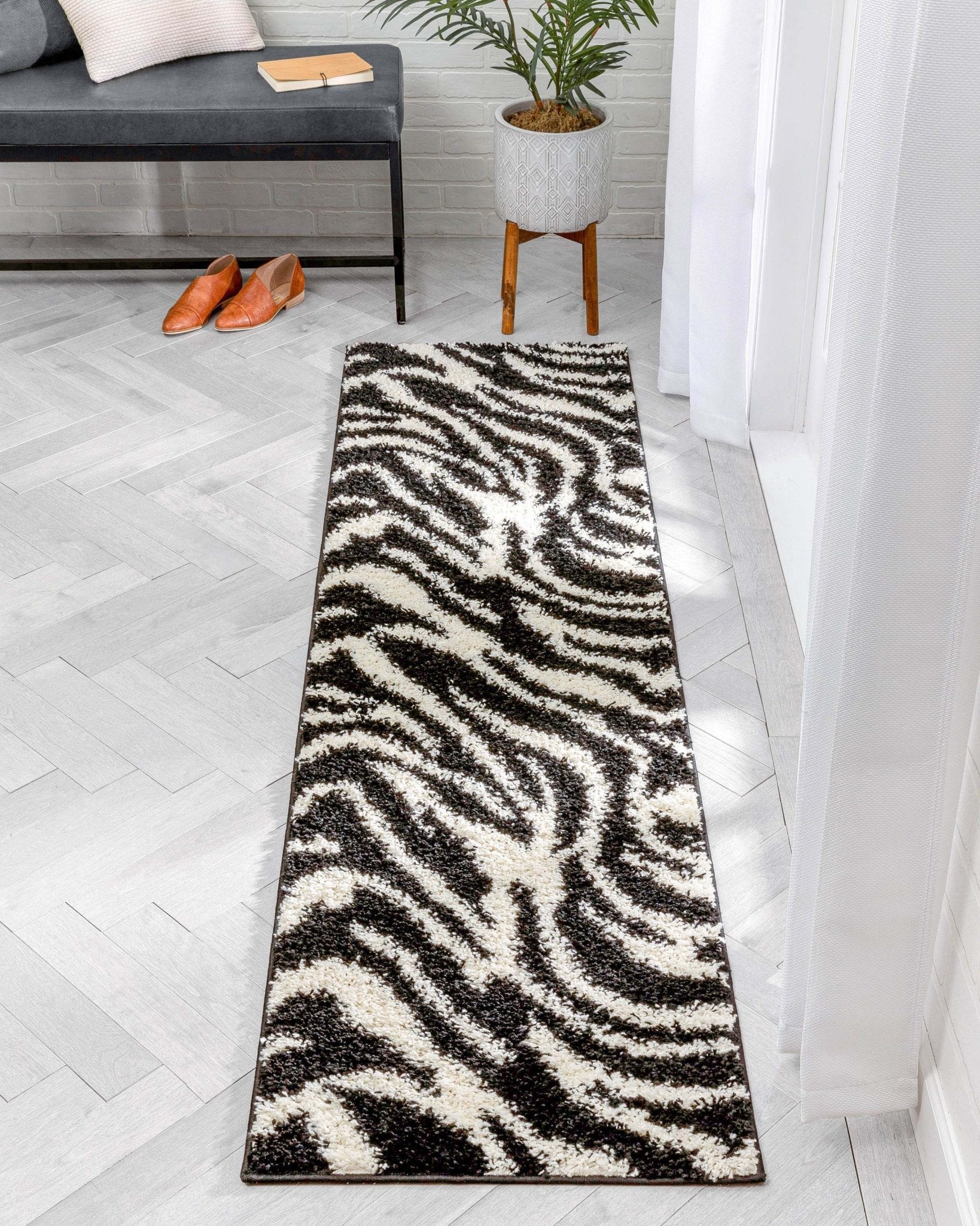 Safari Zebra Black Contemporary Shag Rug - Well Woven - The runner rug styled in a light-filled hallway with white curtains and gray flooring.