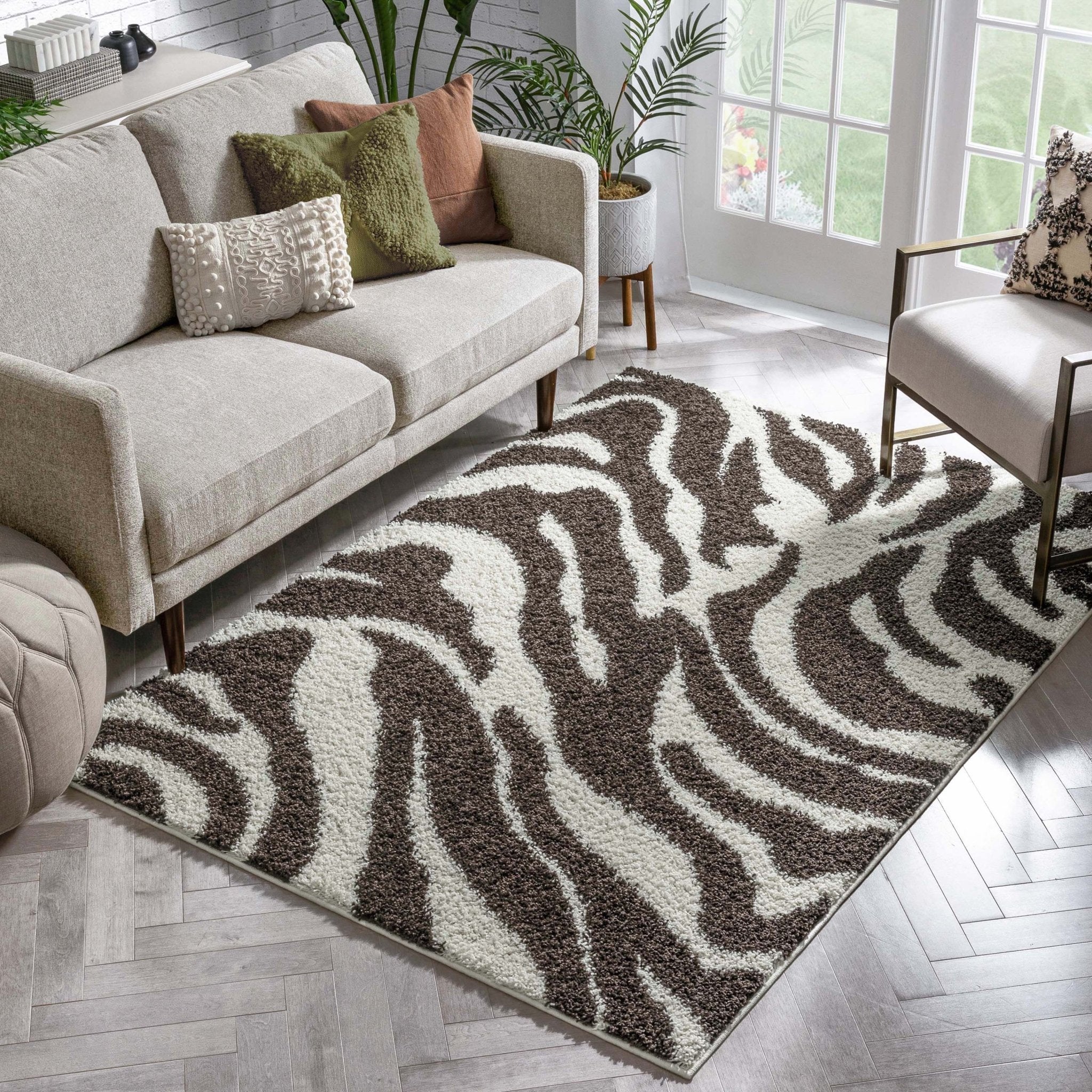Safari Zebra Brown Contemporary Shag Rug - Well Woven - The brown and white zebra rug shown under a sofa and coffee table in a bright living area with white and wood tones.