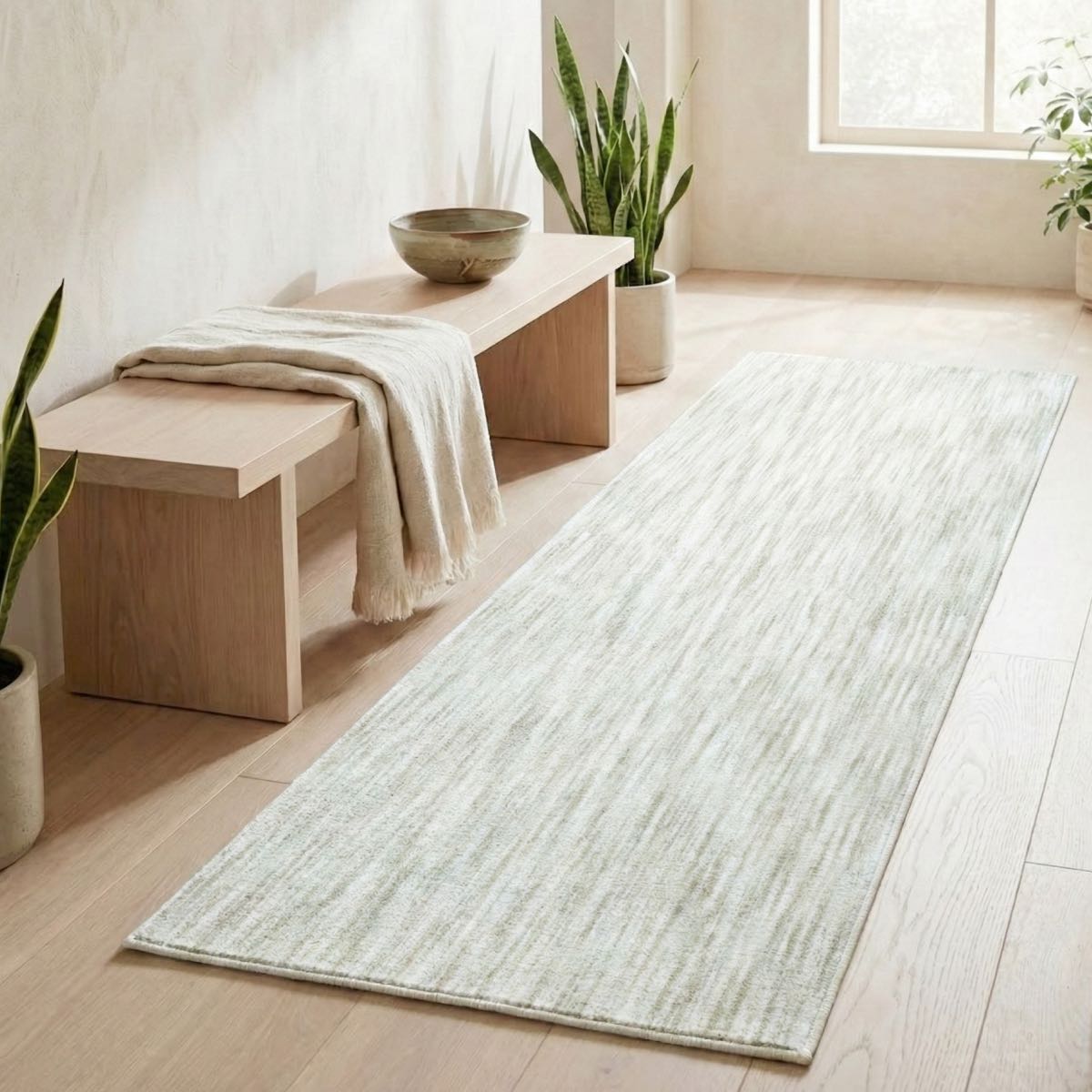 COD-12 - Long rectangular ivory rug on a wooden floor with a bench and plants in a bright room.