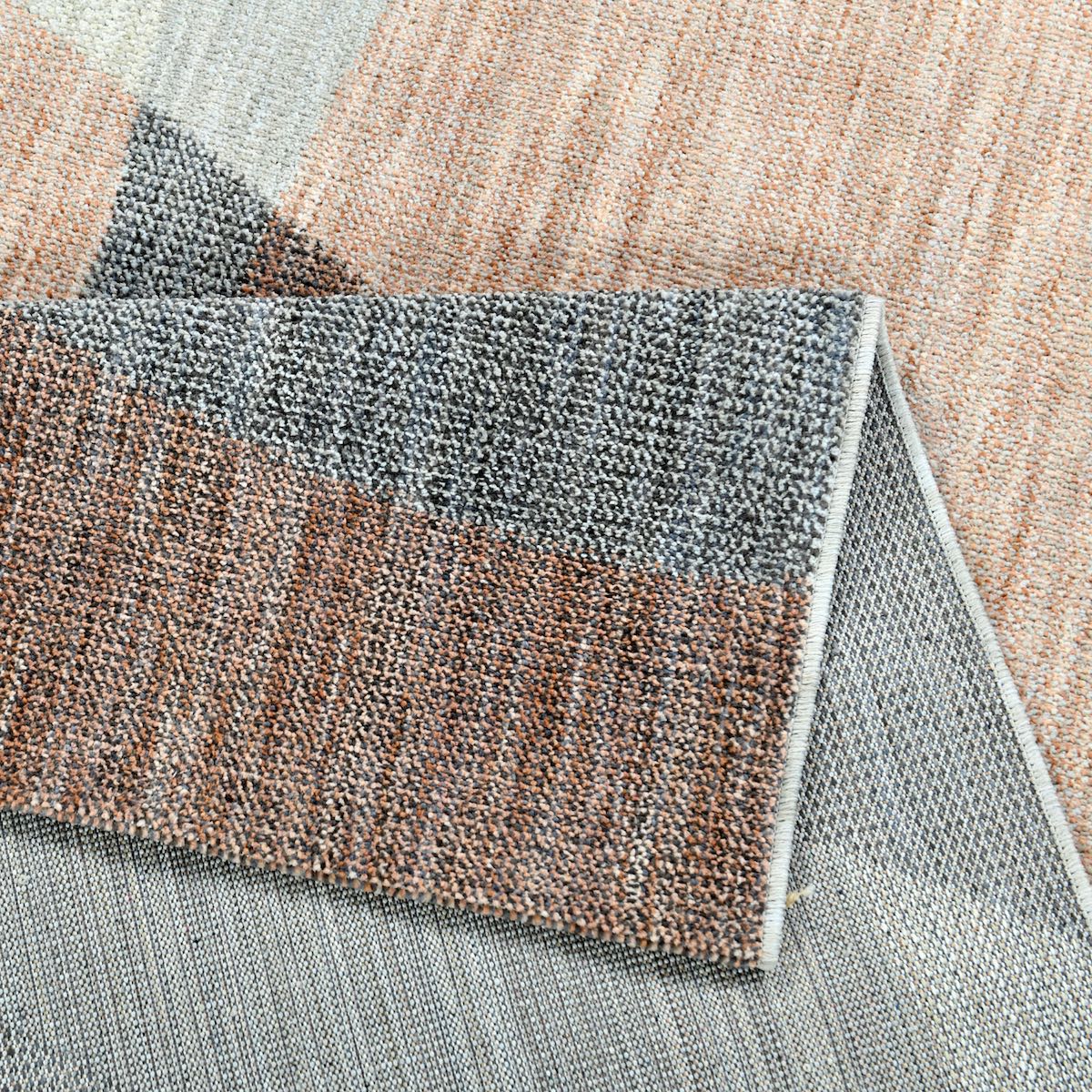COD-60 Well Woven Holt Washable Rug: A close-up of the textured abstract rug with a geometric pattern in shades of peach, gray and beige.