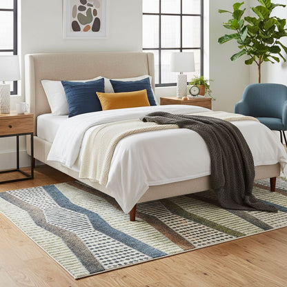 ELM-21 Well Woven Ridge Washable Area Rug: Neatly made bed with decorative pillows on a striped multicolor rug in a bedroom setting