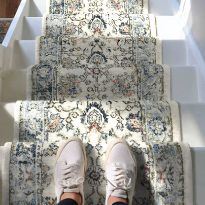 IND-102 Ivory floral patterned staircase runner rug with a person wearing white sneakers on a white staircase.