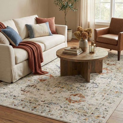 OM-122 – Living room with a cream sofa, a brown accent chair, and a cream vintage distressed rug with rust and gray accents.