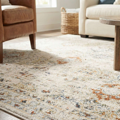 OM-122 – Close-up of a cream vintage distressed rug with rust and gray accents in a living room setting with wood flooring and upholstered seating.
