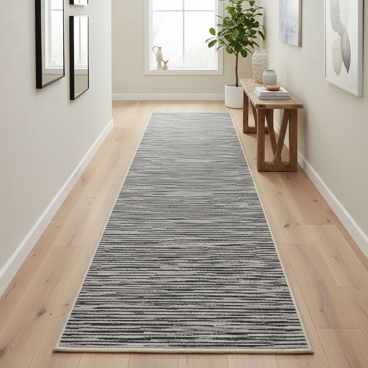Custom size modern striped fogstone and pewter hallway runner rug by Well Woven, styled in a bright minimalist hallway with light wood floors, a slim console table, wall art, and a potted plant near a window.