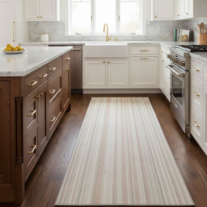 Neutral striped kitchen runner rug on dark wood floor in a modern white kitchen. The multi color runner is Apollo Seabreeze Lines Moonlit Ivory from Well Woven.