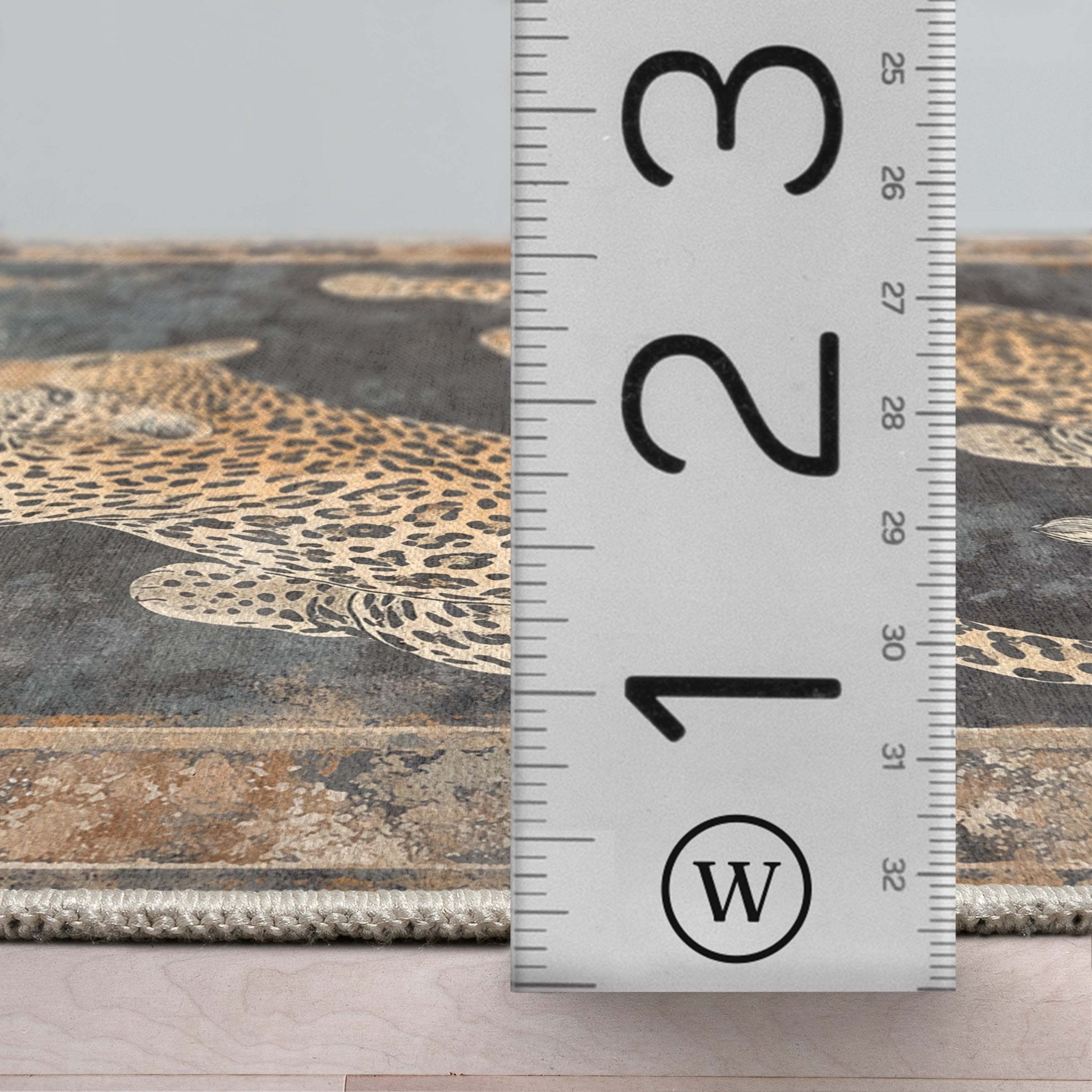 A detail image of the Leopard’s Reverie Charcoal & Natural Rug's profile with a ruler showing the rug's thickness
