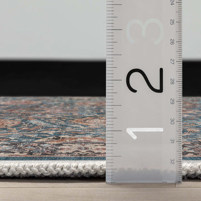 Close up profile of the Asha Liana Teal Flatwoven Runner Rug with a ruler showing measurements on a wooden floor. 
