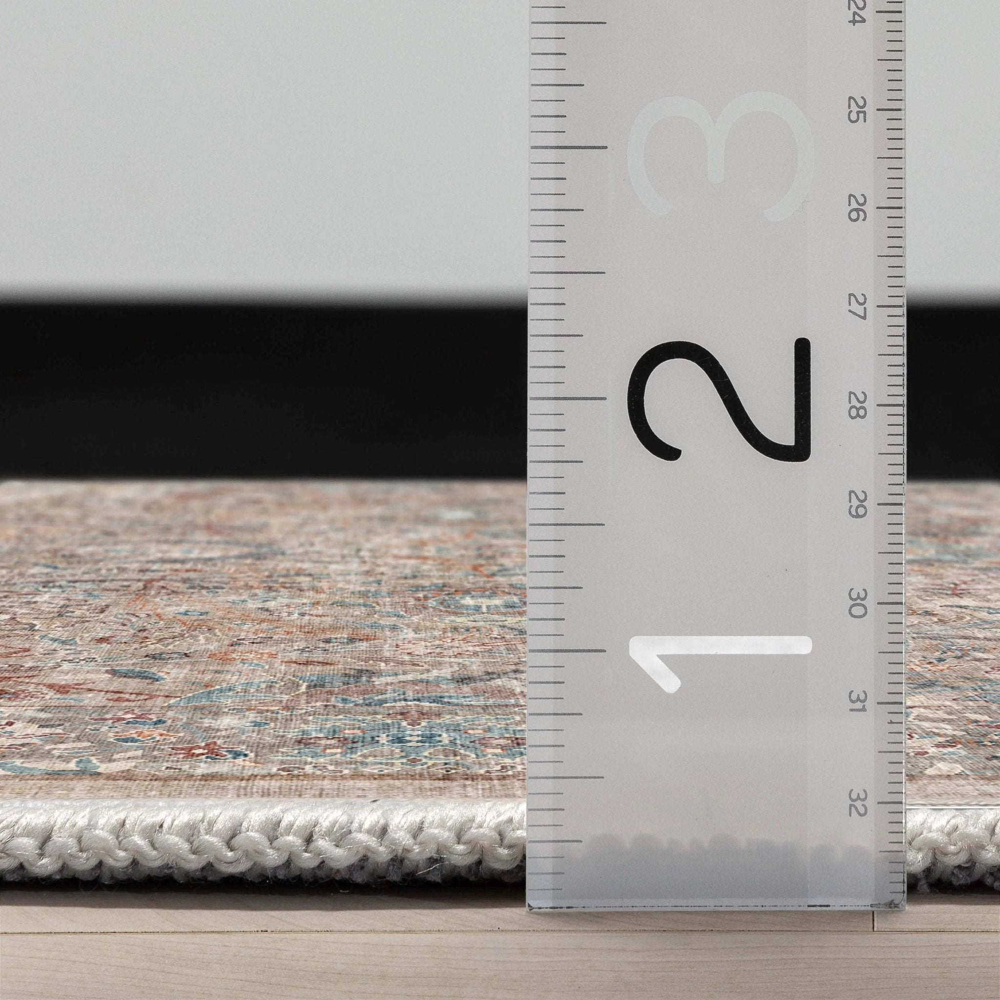 A side profile of the Asha Emilia Flatwoven Custom Runner Rug with a ruler showing measurements on a wooden floor