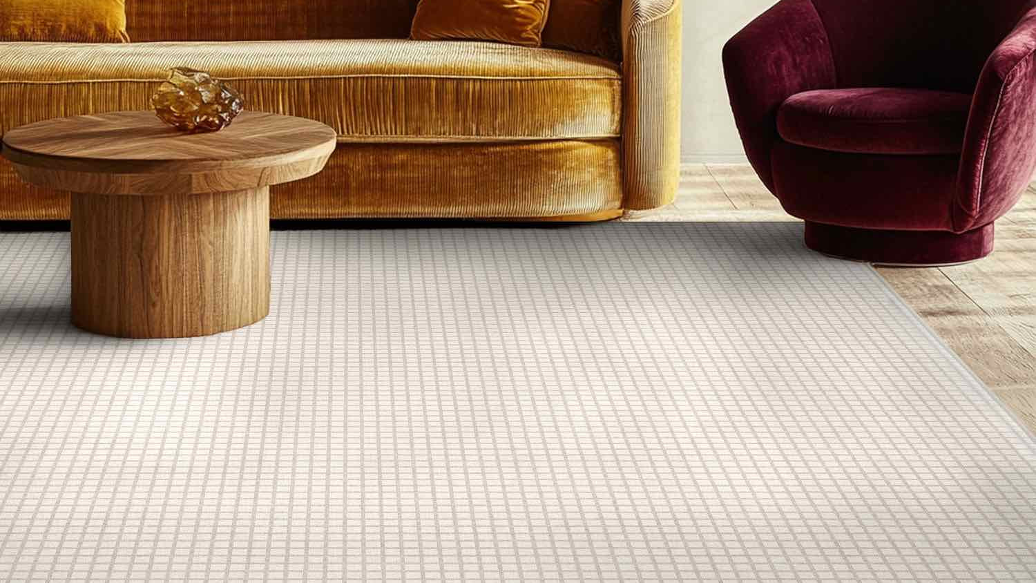 Modern living room with a brown velvet sofa, wooden coffee table, and burgundy armchair. A white custom rug with a windowpane grid pattern from Well Woven anchors the space.