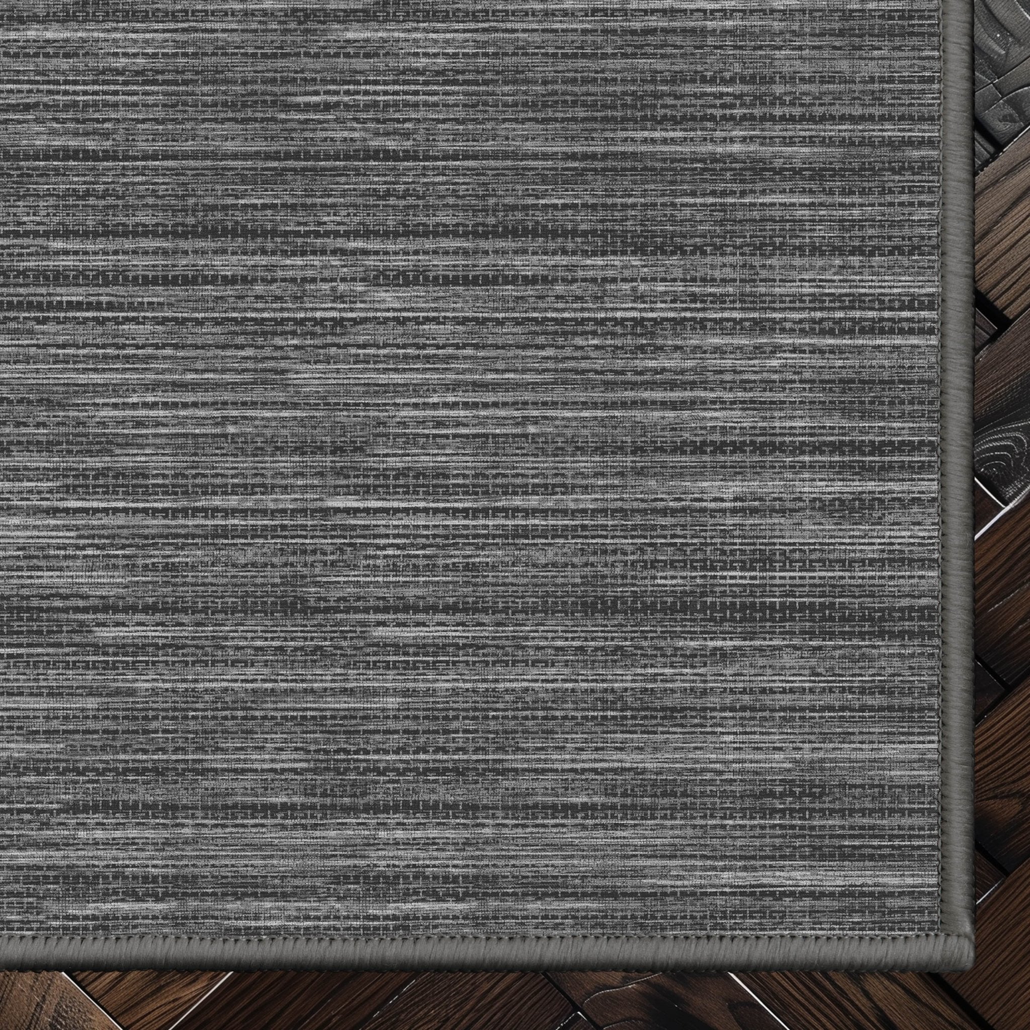Edwin Custom Rug - Monochrome Striation , Flat Pile, Easy  Clean, Customizable for Your Space - Well Woven - Top-down corner image showing the rug’s smooth, uniform weave and cool dark grey toned rug color.