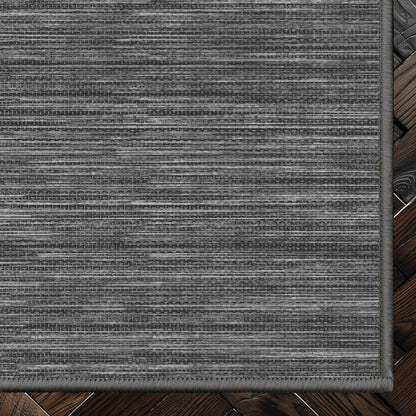 Edwin Custom Rug - Monochrome Striation , Flat Pile, Easy  Clean, Customizable for Your Space - Well Woven - Top-down corner image showing the rug’s smooth, uniform weave and cool dark grey toned rug color.