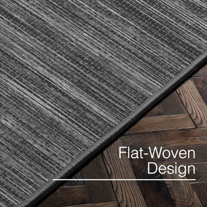 Edwin Custom Rug - Monochrome Striation , Flat Pile, Easy  Clean, Customizable for Your Space - Well Woven - Angled close-up of the dark grey rug with text: “Flat-Woven Design.”