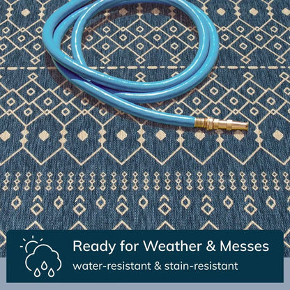 Nord Moroccan Tribal Indoor Outdoor Blue Flatweave Rug Well Woven - Close-up of a hose rinsing the outdoor rug, indicating it’s “Ready for Weather & Messes.”