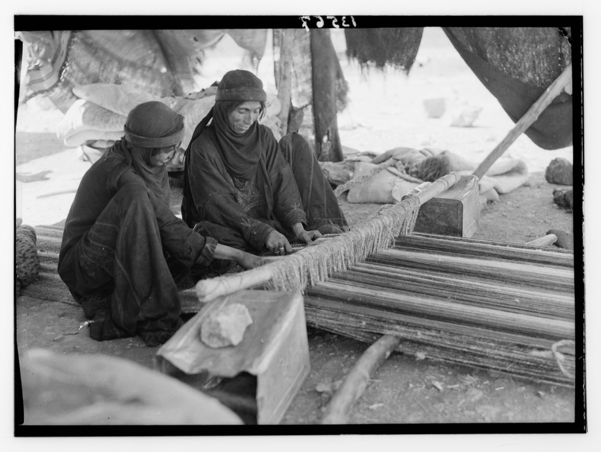 Bedouin women weaving on a ground loom staked low to the earth.