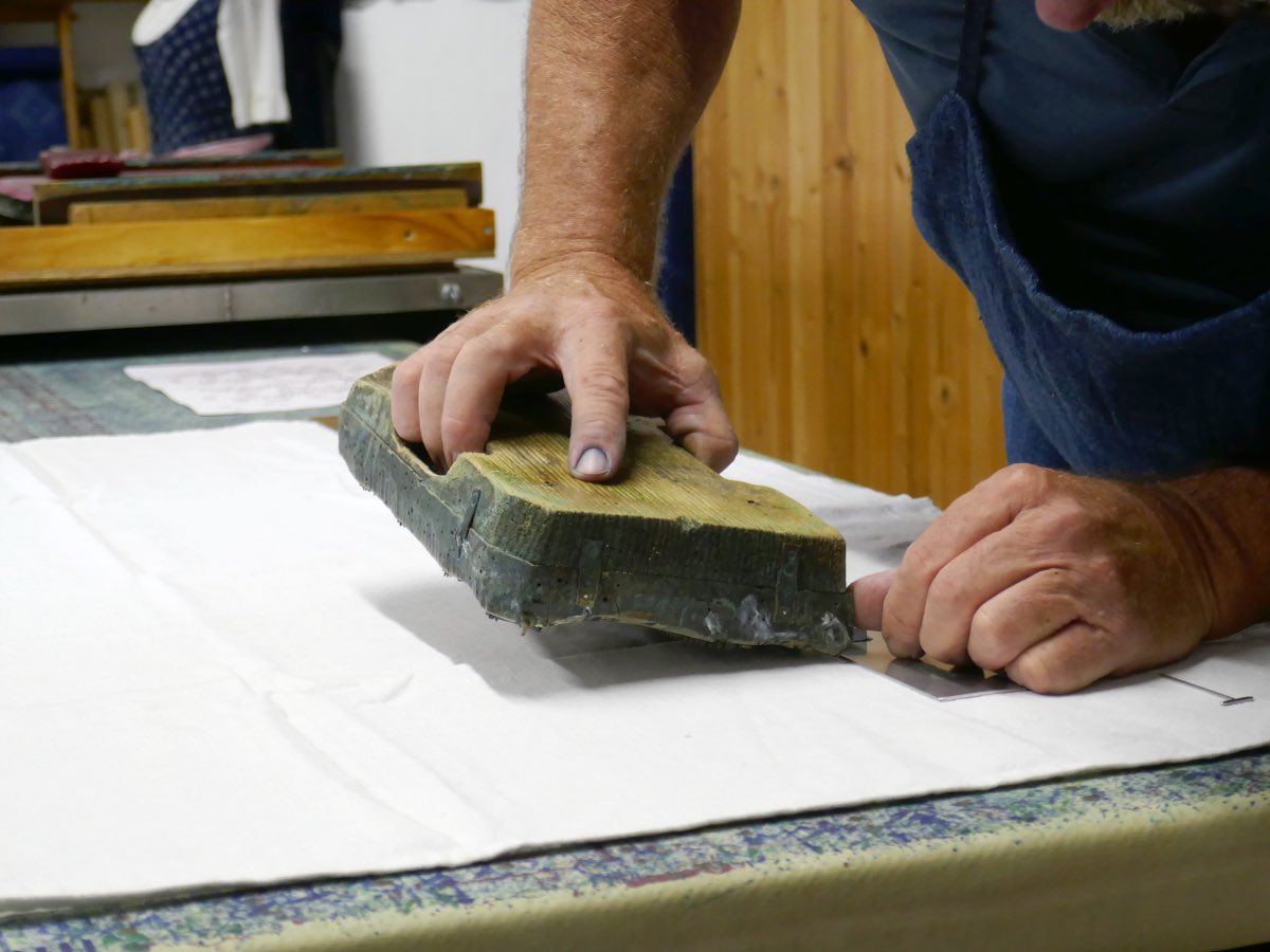 A printer pressing a carved wooden block onto cloth at the Wagner blueprint workshop in Bad Leonfelden, Austria.