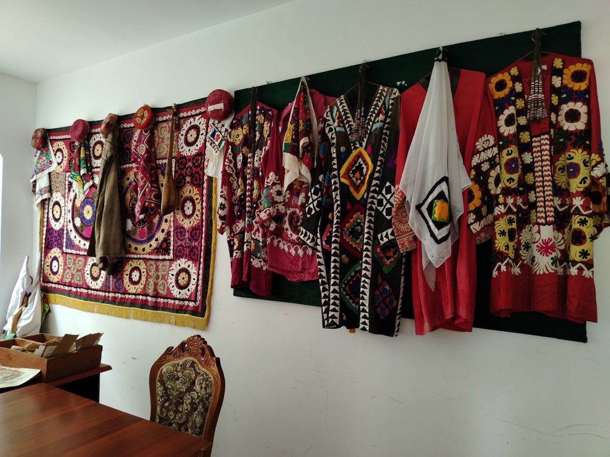 Chakan-embroidered dresses and hangings on a museum wall in Khatlon, Tajikistan — the craft's heartland.