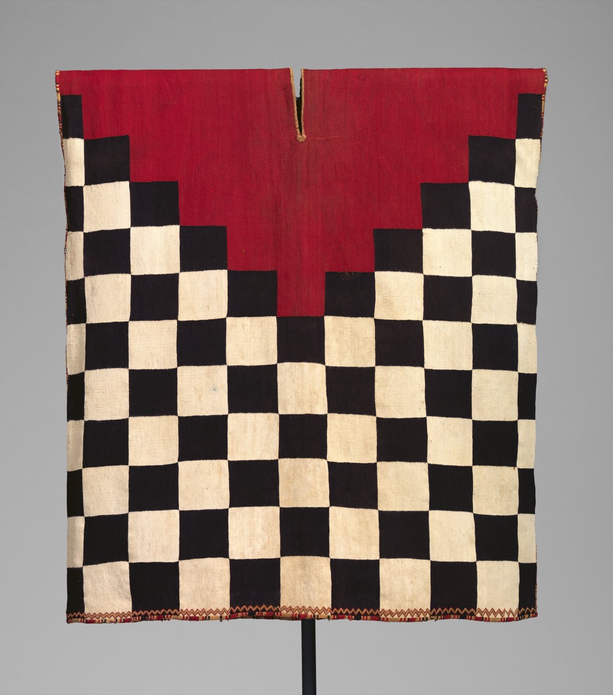 A 16th-century Inca tapestry-woven tunic — the black-and-white checkerboard pattern worn by imperial soldiers.