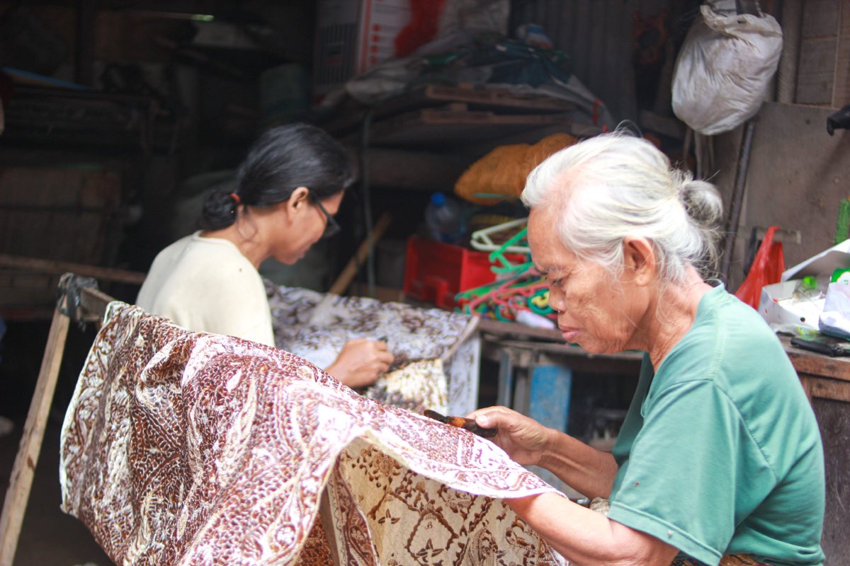 A mother and daughter drawing hot wax onto stretched cloth with canting pens in Trusmi, Cirebon.