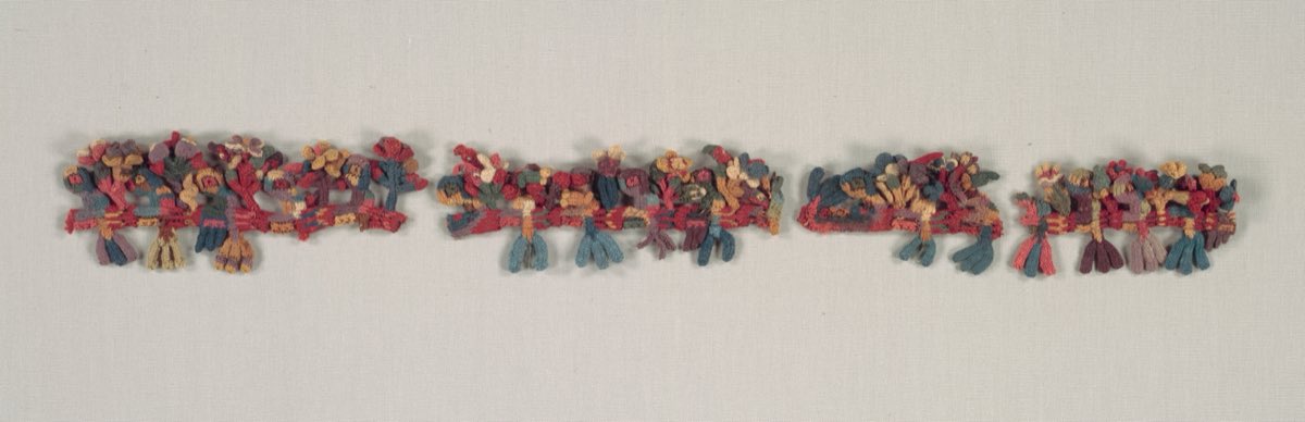 A Nasca border fragment worked in cross-knit looping — tiny three-dimensional birds and flowers, around 2,000 years old.
