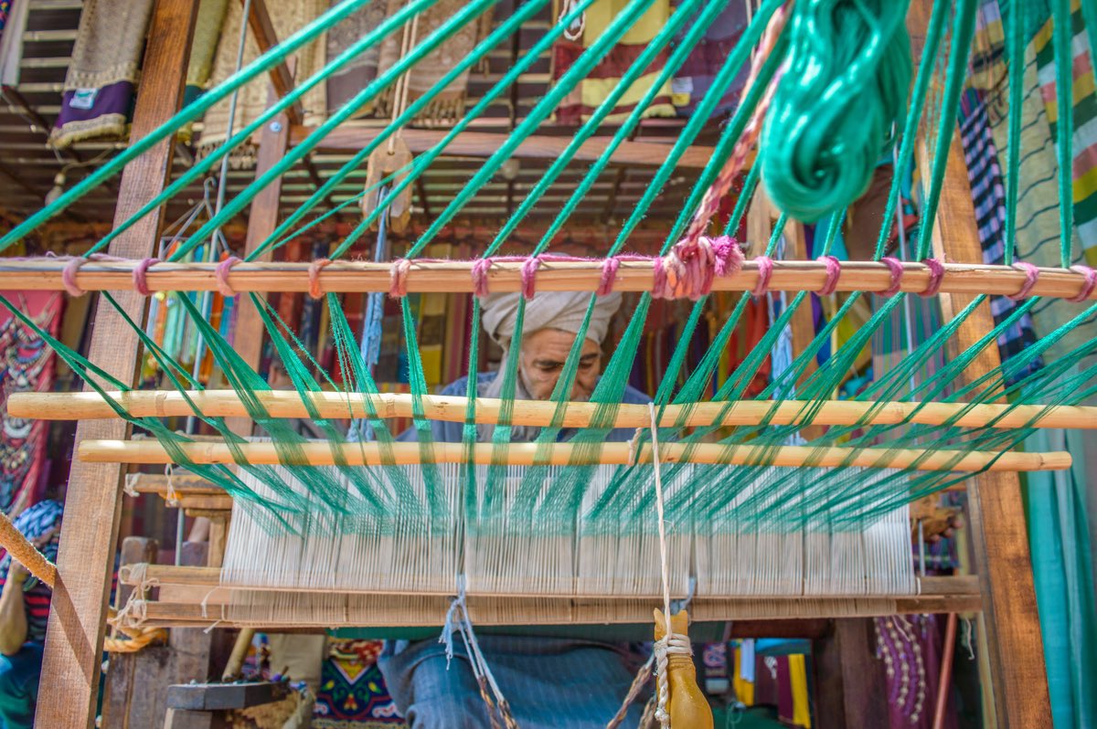 An Egyptian weaver working at a traditional wooden handloom.